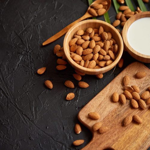 close up of almonds in wooden bowl and almond milk utc